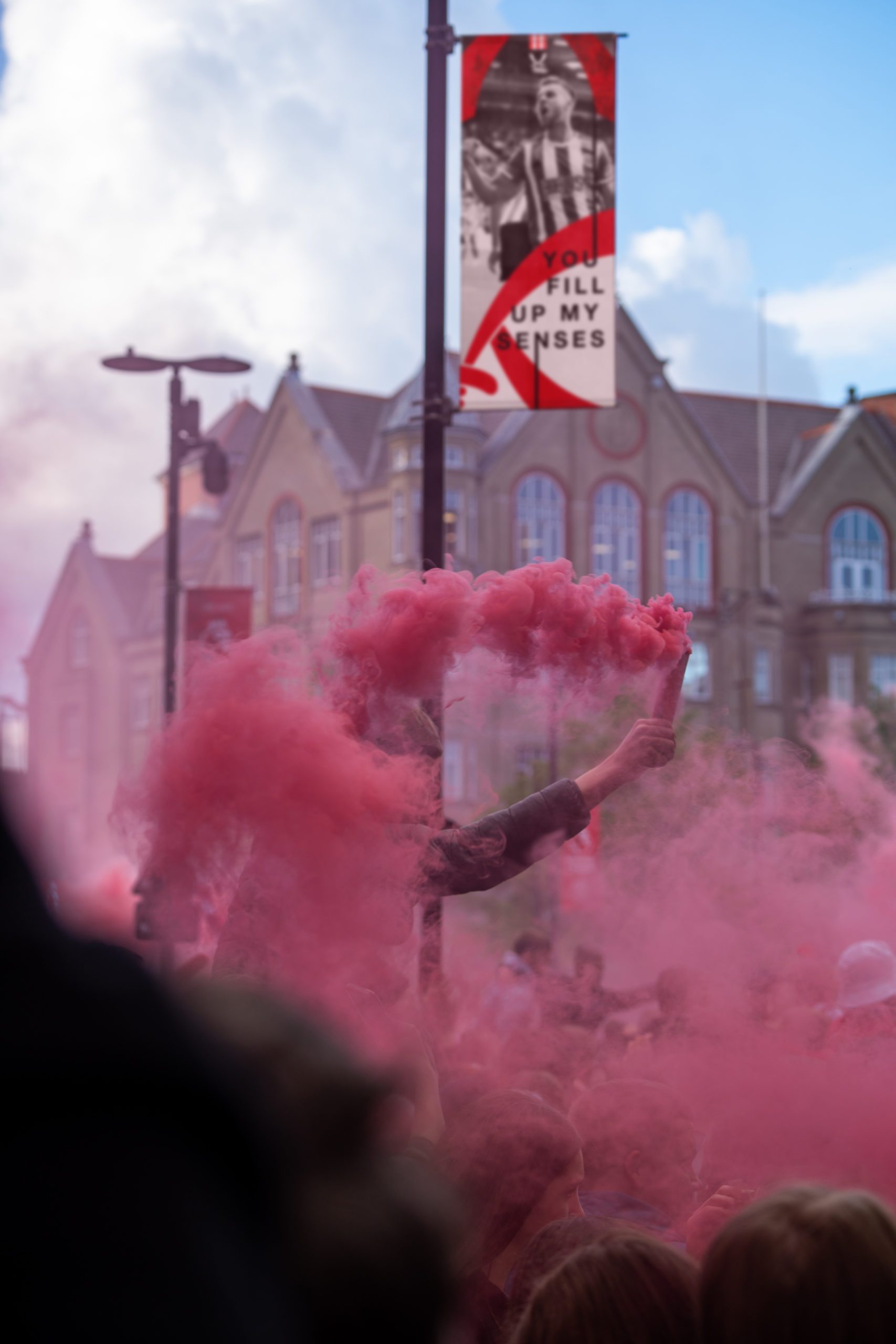 A fan holding up a flare when Sheffield United got promoted to the Premier League. In the background is a flag which PWF Studio created