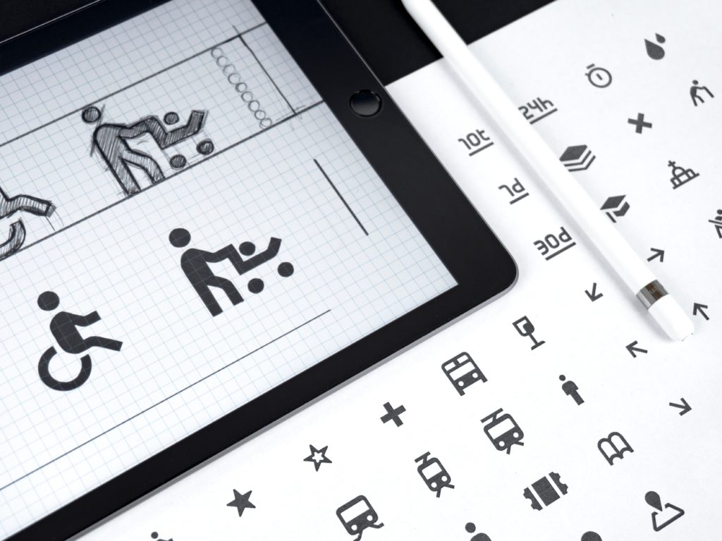 A tablet and print out showing various icon designs