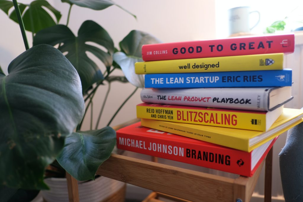 A stack of design books with a plant in the background