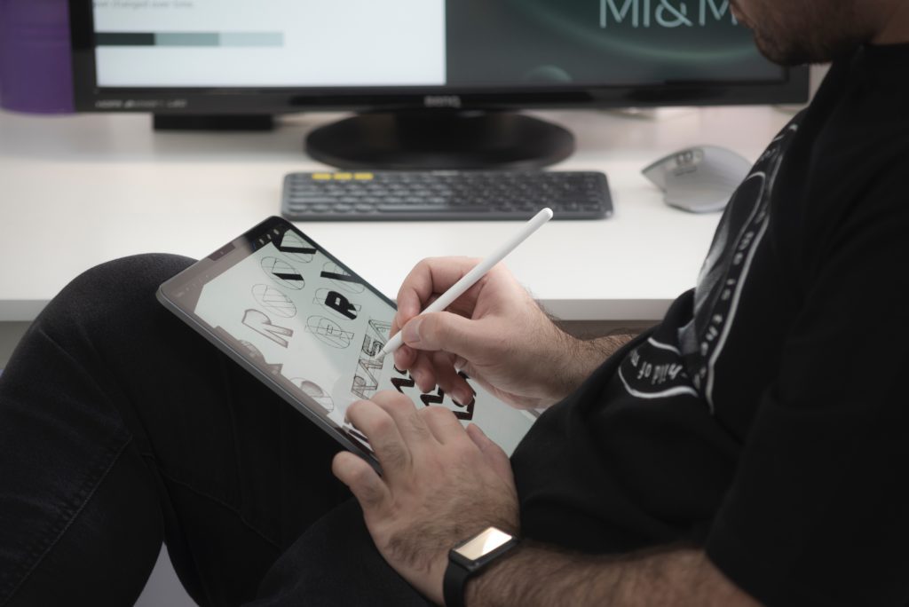 A man drawing a selection of logos on a tablet